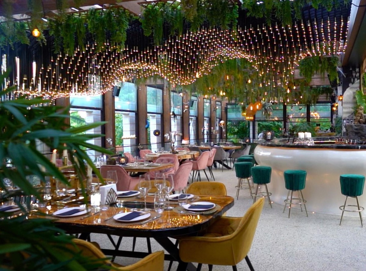 sala d emese de la restaurant Kong, cu mobilier modern, in culorile verde, alb si auriu, cu plante decoratove pe tavan si beculete aprinse, restaurant potrivit pentru petrecerea de Crăciun a firmei