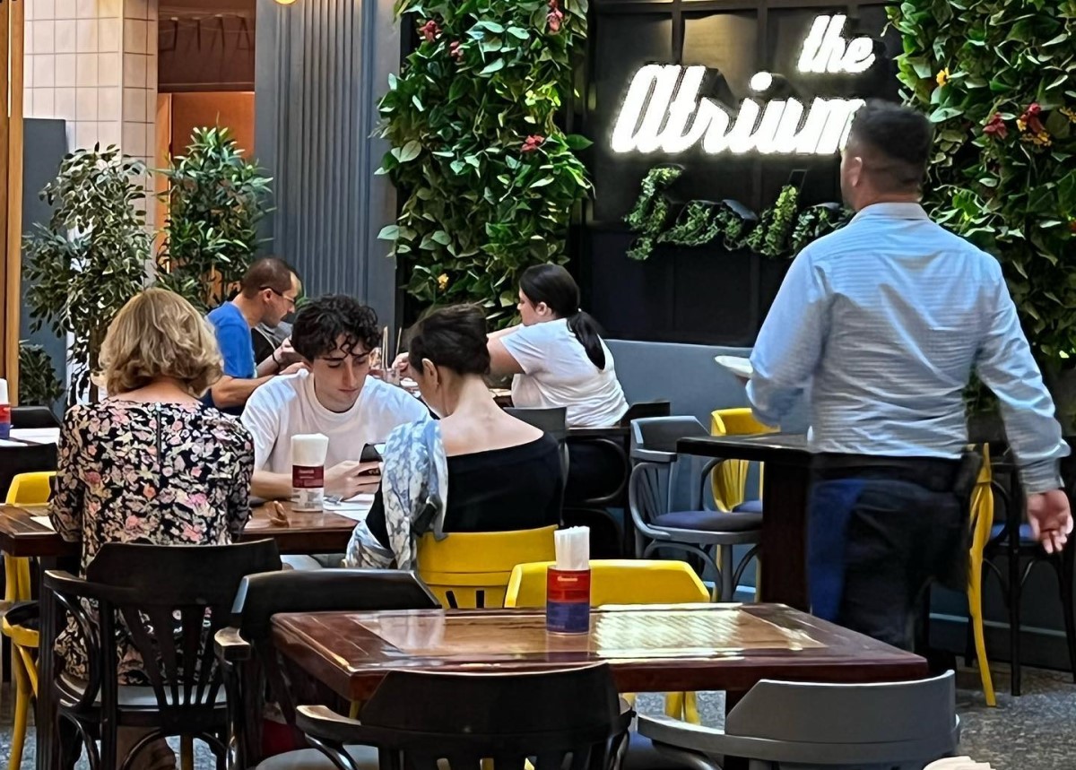osptar care trece cu o tava in mana printre mesele cu clienti la Stadio Union, un restaurant unde să iei masa de prânz dacă lucrezi în Centru