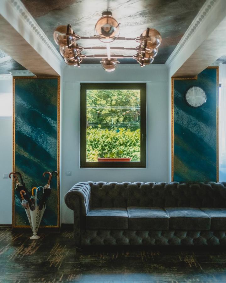 canapea masiva de catifea albastra in dreptul unei ferestre la Suru Hotel
