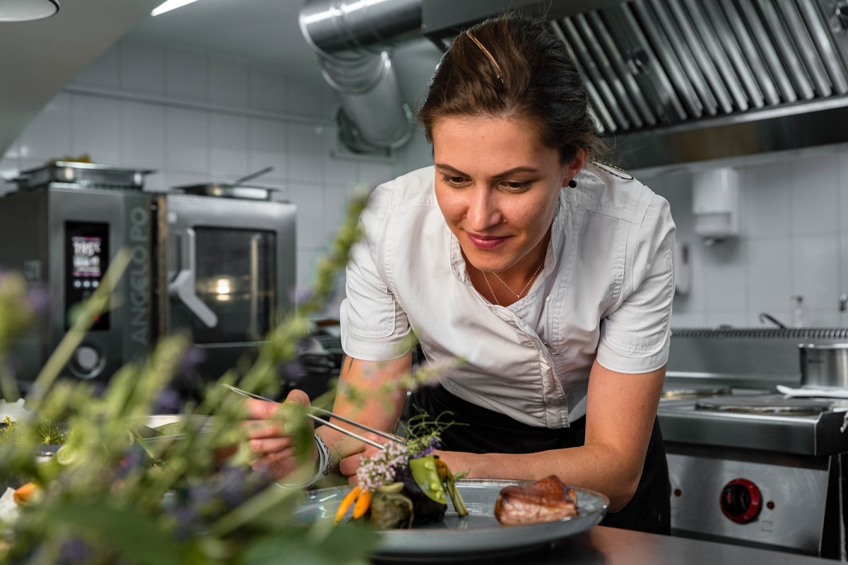 Chef Madalina Roman, aplecata asupra bancului sau de lucru din bucataria profesionala de la restaurant Szikra din Sf. Gheorghe, cu bucătărie românească modernă