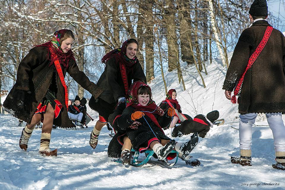 copii mai mici si mai mari imbracati in costume traditionale romanesti, la sanuis iarna, pe o partie printre copaci