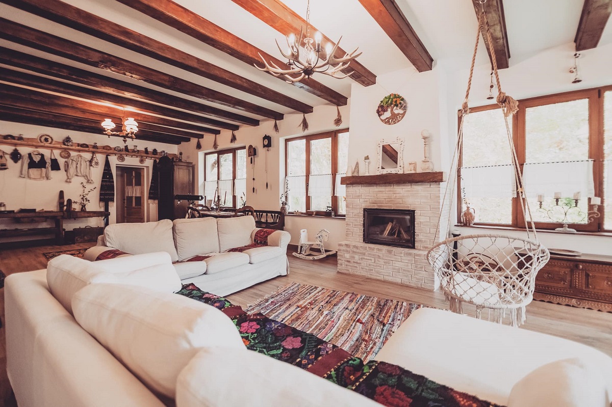livingul de la Casa de sub Munte, cu canapele ample, comode, albe, cu semineu alb si tavan cu barne, una din pensiuni cu ciubăr