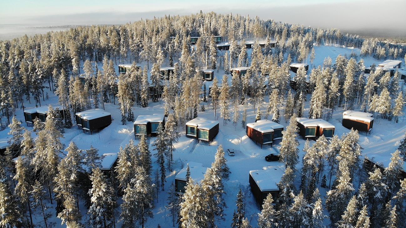 casute de lemn rasfirate printre barzi, totul acoperit de zapada, acasă la Moș Crăciun în Rovaniemi, Laponia