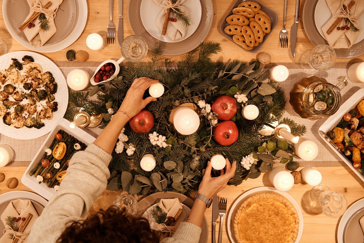 masa de Craciun fotografiata de sus, in centru cu un arnajament din crengute de brad si farfurii cu mancare după rețete vegetariene pentru masa de Crăciun