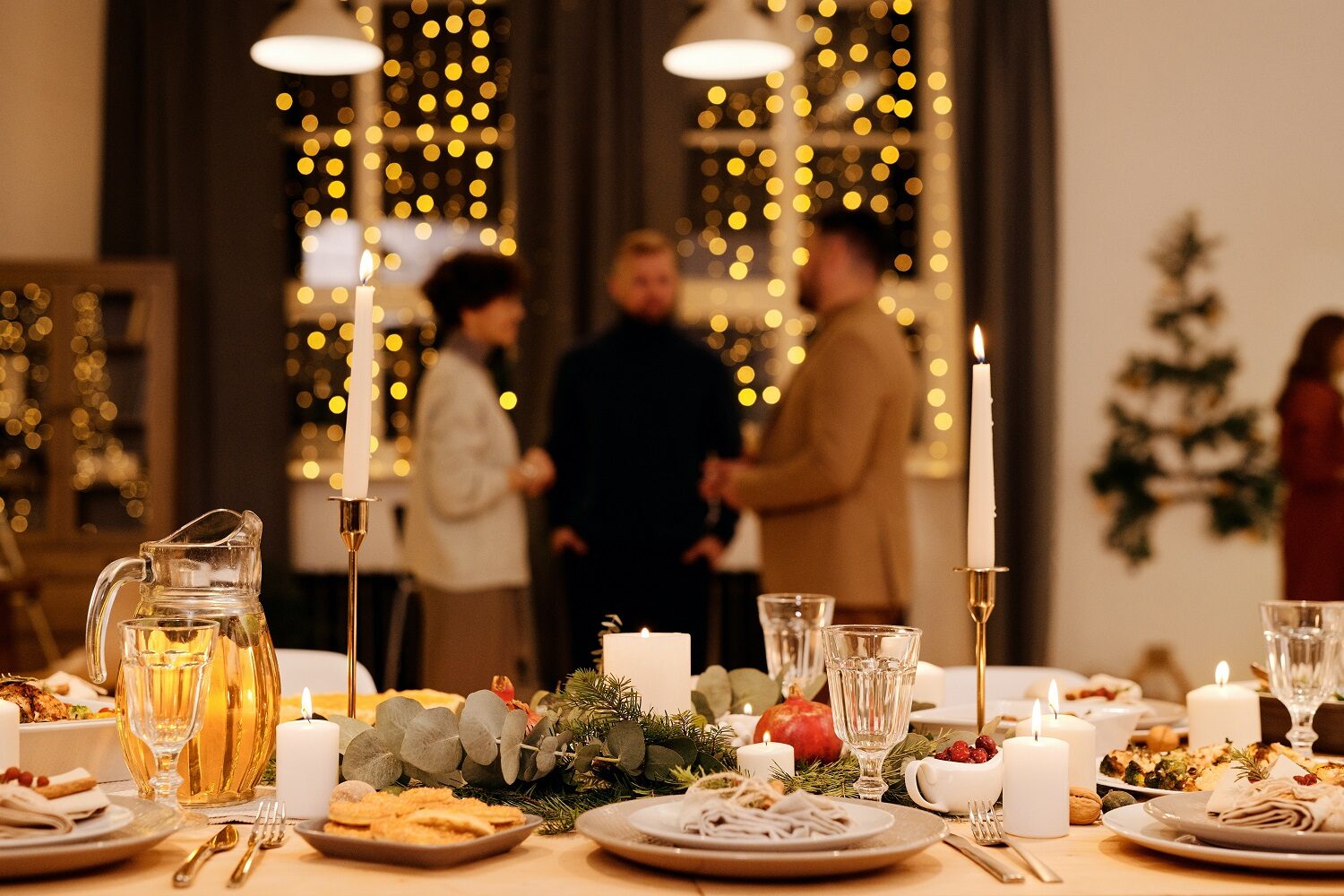 prim plan cu o masă frumos decorată de Crăciun, iar in fundal 3 oameni care stau de vorbă