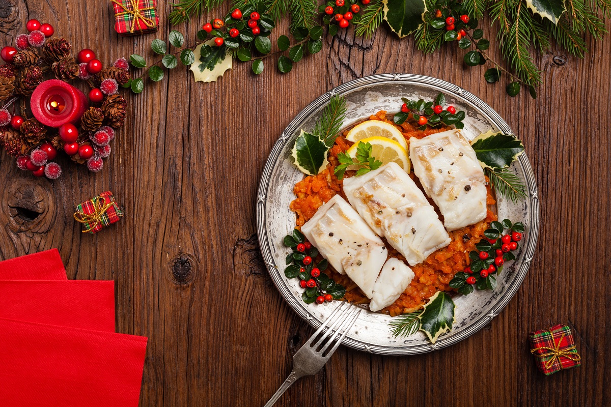 Christmas fish. Roasted cod pieces, served in vegetable sauce. Xmas styling. Top view.