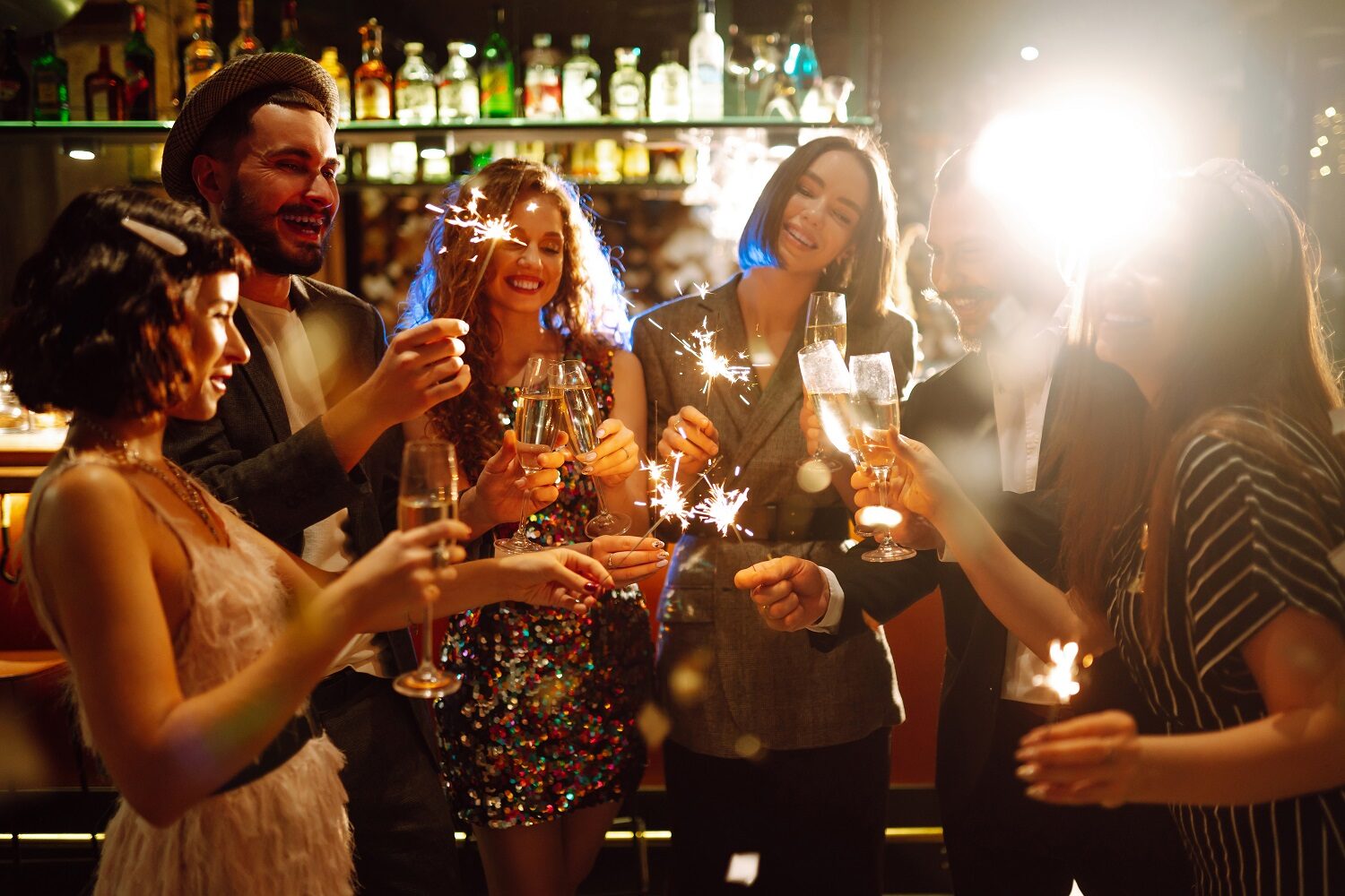 prieteni la o petrecere de Revelion într-un bar, cu băuturi și artificii în mână