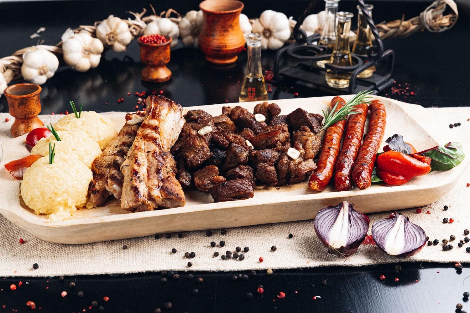 platou tradițional cu carne la garnita, carnati de casa, muschi de porc si mamaliga pe un platou alb , fotografiat pe fundal negru - pomana porcului la Taverna Sârbului
