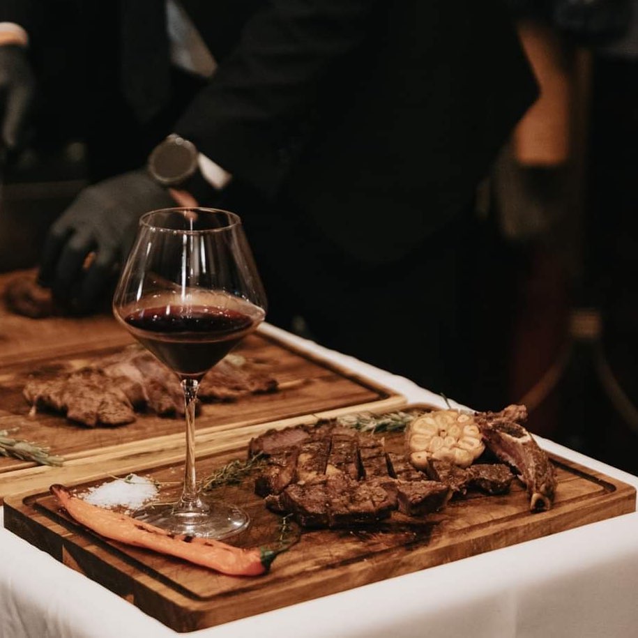 steak de vita servita pe platou de lemn alaturi de un pahar cu vin rosu la Fenice Palas restaurante bune Iași