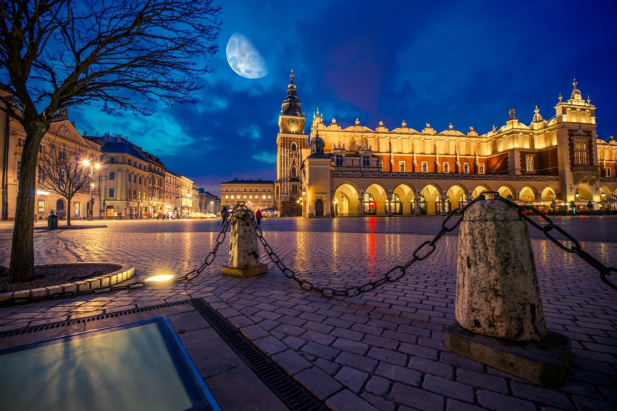 Krakow Main Market Place After Dark with Moon on the Sky. Cracow, Lesser Poland, Europe.
