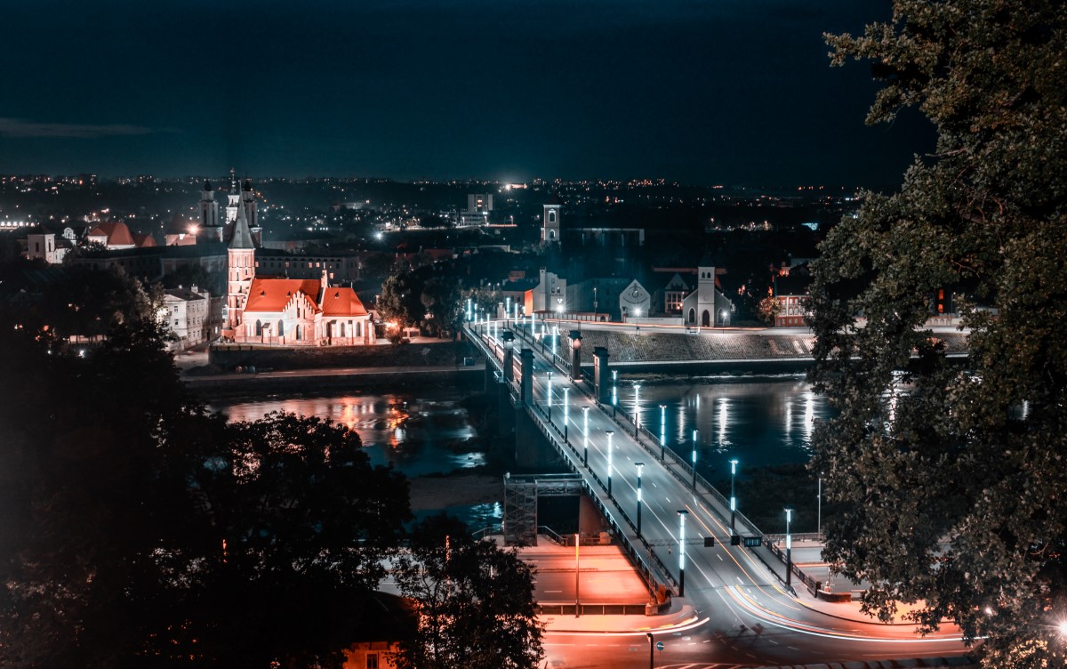 pod din orasul Kaunas, Lituania, fotografiat seara, cu lumini aprinse si orasul in fundal