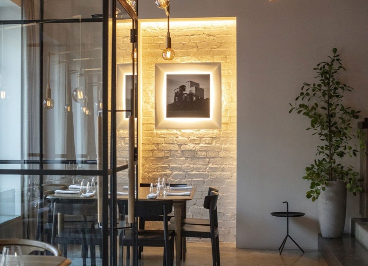 masa in restaurantul Nüman din Kaunas, Lituania, cu pereti albi, un tavan atarnat in dreptul mesei si un corp de iluminat, decorat minimalist - unul dintre cele mai romantice restaurante din Europa