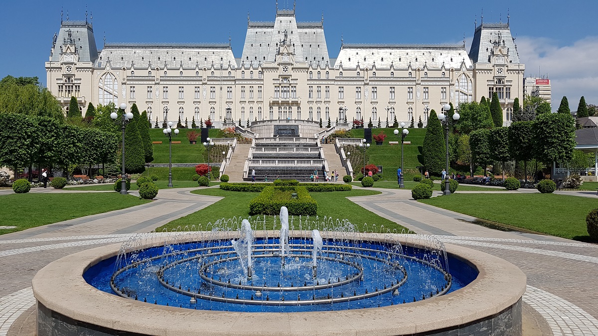Palatul Culturii din Iași fotografiat din departare, iar in prim plan o fantana si aleile parcului din fata Palatului