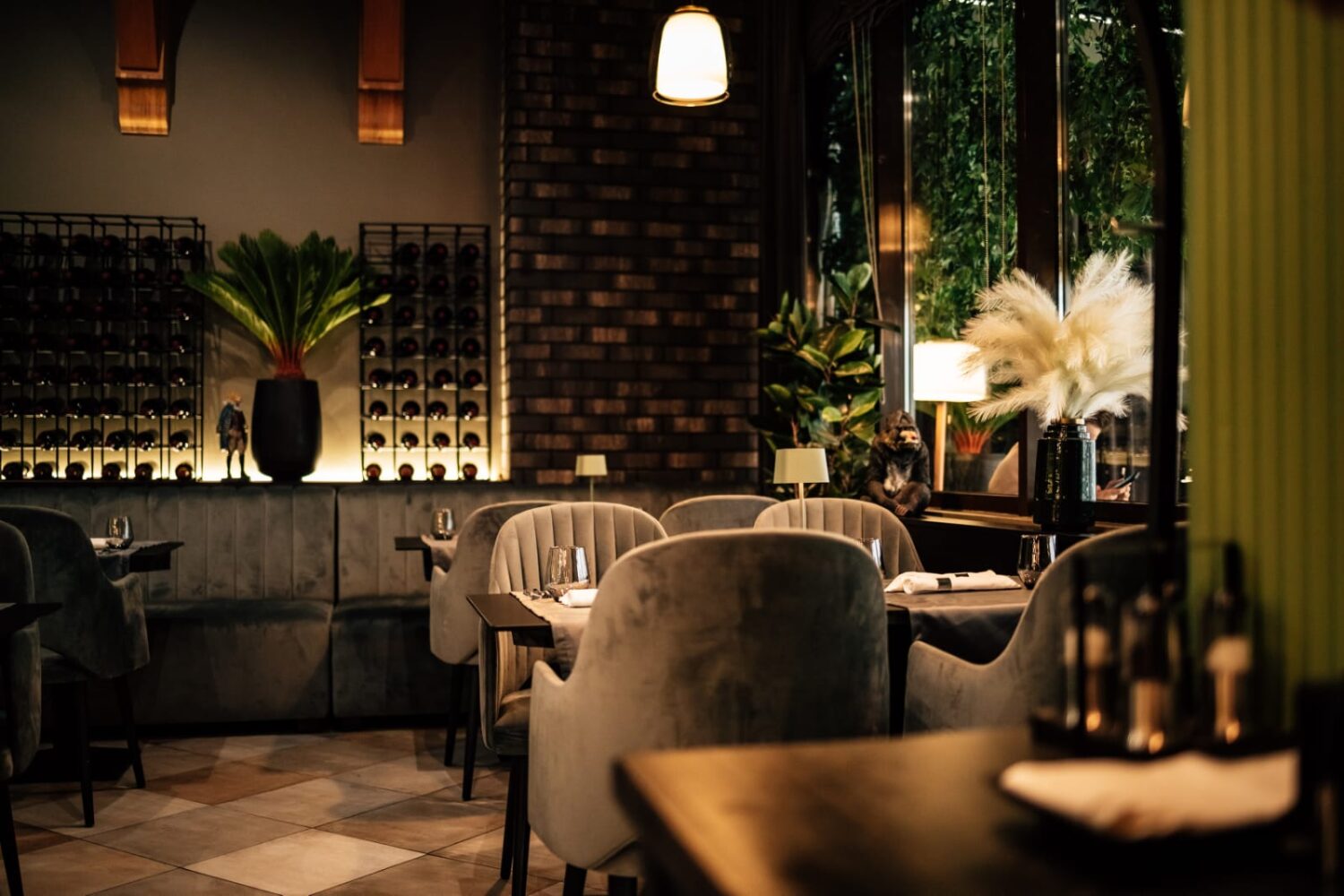 mese cu scaune capitonate, bej, iar in fundal barul cu rafturi cu stile, totul in lumina difuza, la restaurant L’Evoque 360, unul din restaurante romantice București