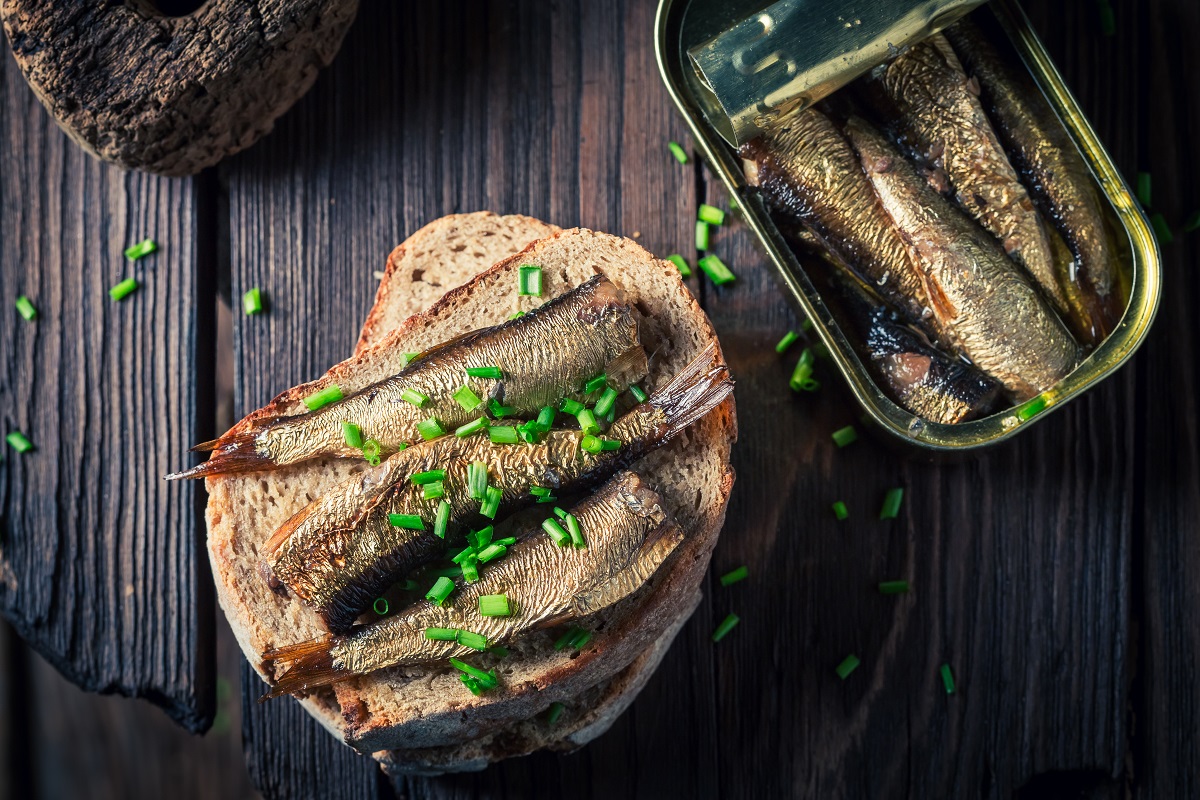 sandwich cu sardine, chive si paine integrala, langa o conserva cu sardine - tinned fish food trends 2023