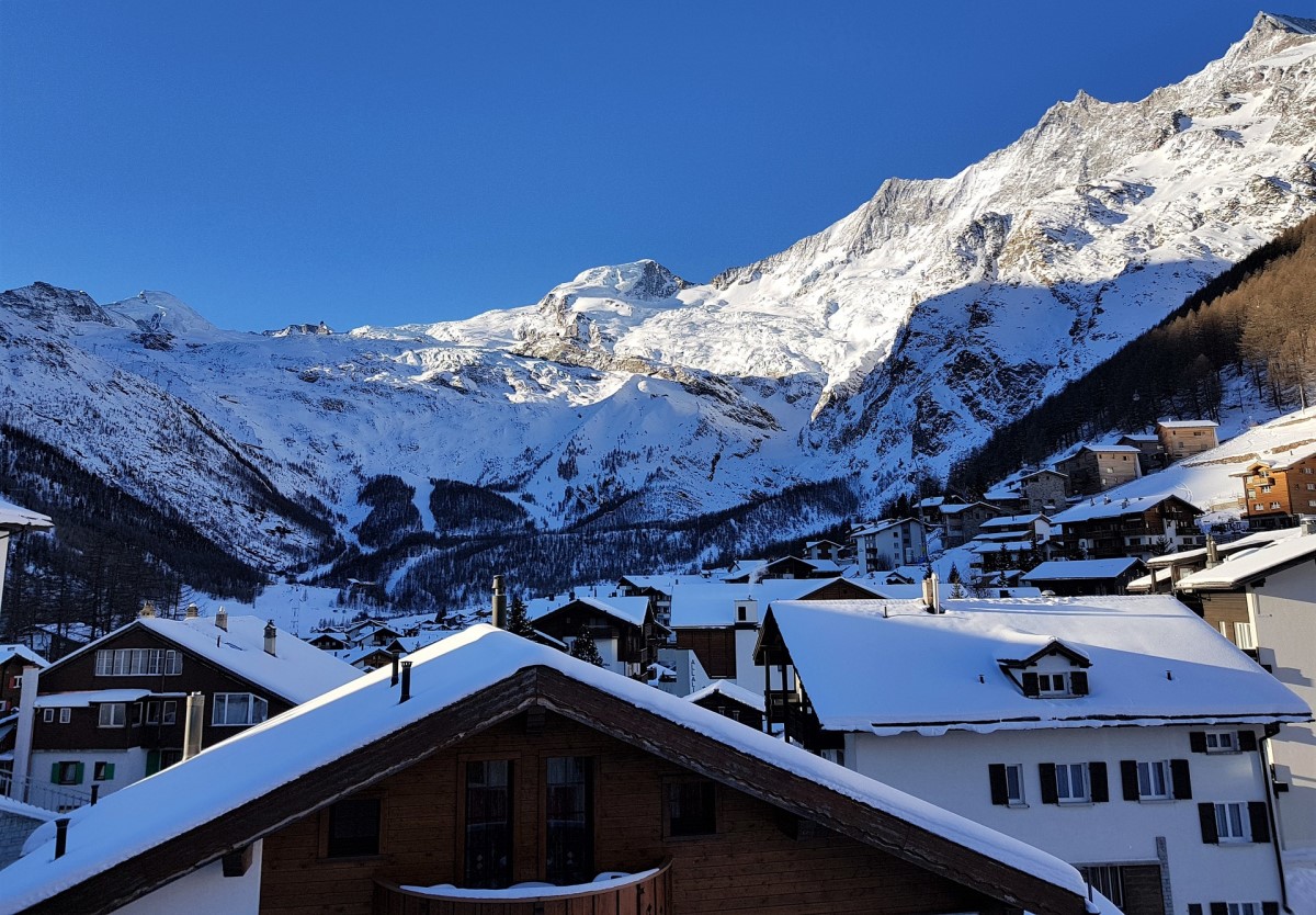 acoperisul caselor din statiunea  Saas-Fee , acoperite de zapada, iar in fundal muntele unde să mergi la schi în Elveția