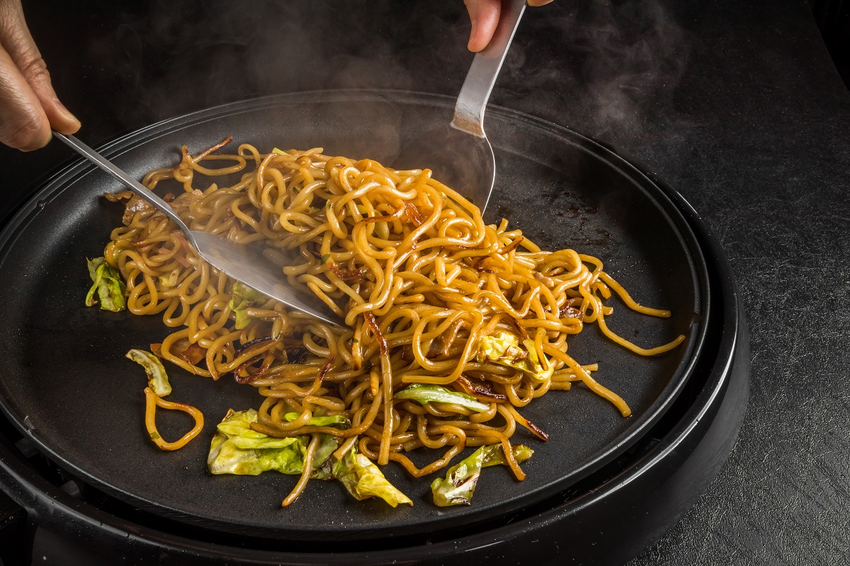 farfurie neagra in care cineva amesteca o portie de chow mein - tipuri de noodles asiatici