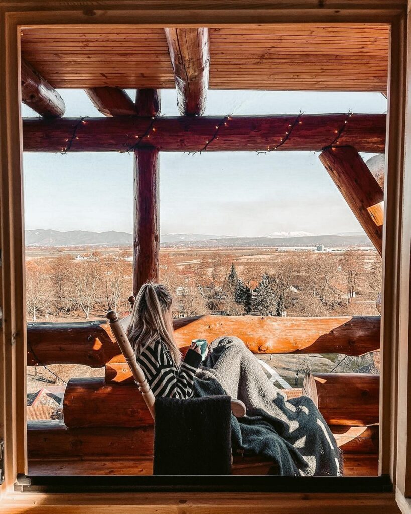 femeie care admira perisajul dintr-un sezlong, pe pridvorul Transylvania Log Cabins