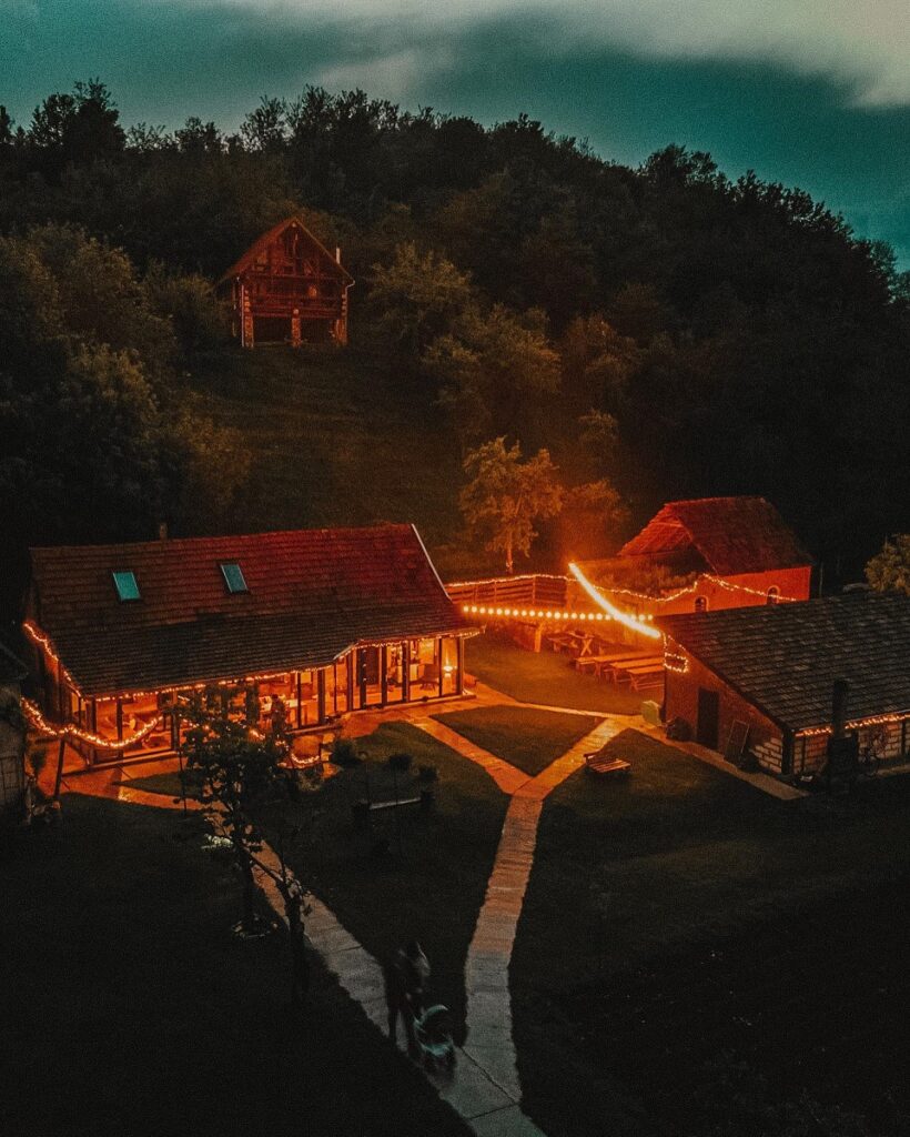 ansamblul de casute de la Transylvania Log Cabins, fotografiat seara, cu luminile aprinse la case si beculete ornamentale aprinse