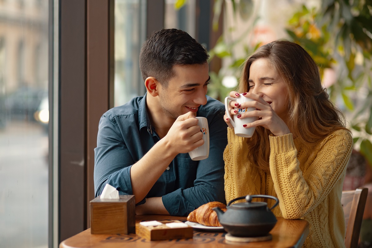 Young attractive couple on date in coffee shop. In love man and woman sitting in a cafe, drinking coffee - vodul bunelor maniere la date