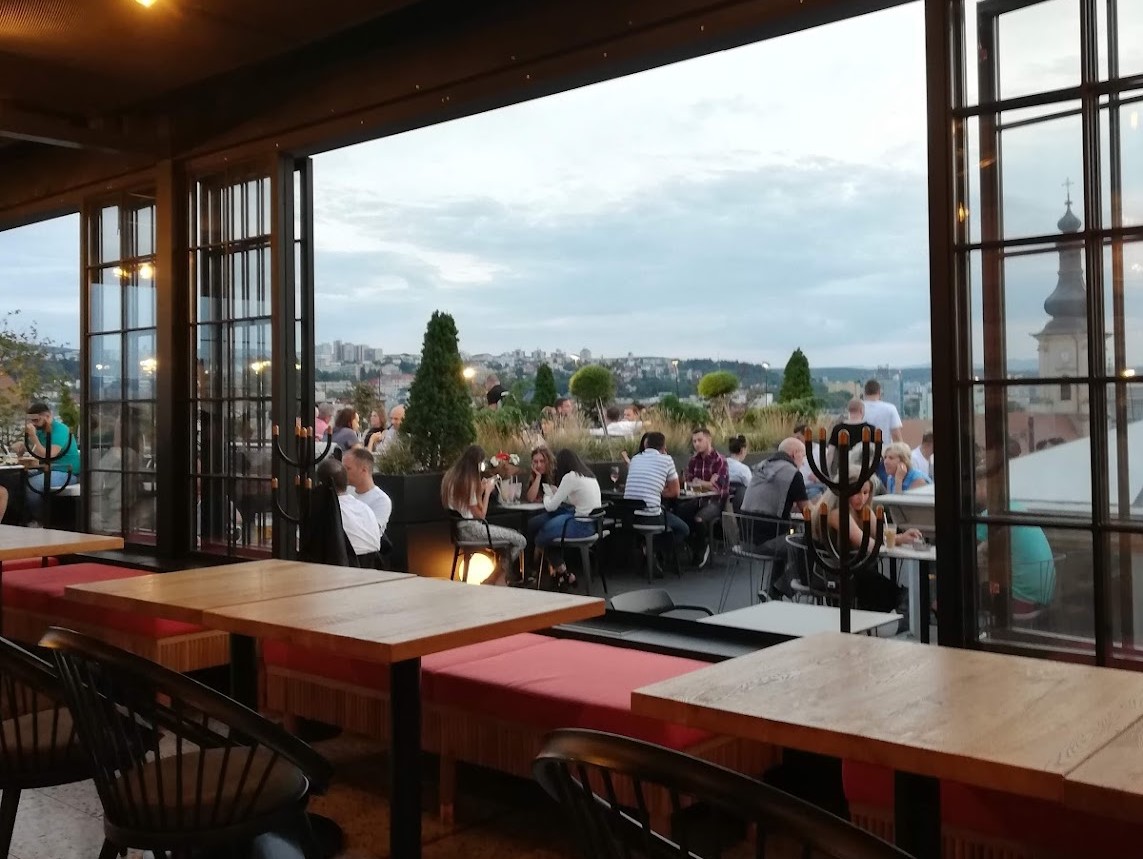 clienti care iau masa pe terasa la Klausen Burger Brewpub & Rooftop restaurant din Cluj, unul din restaurante skybar