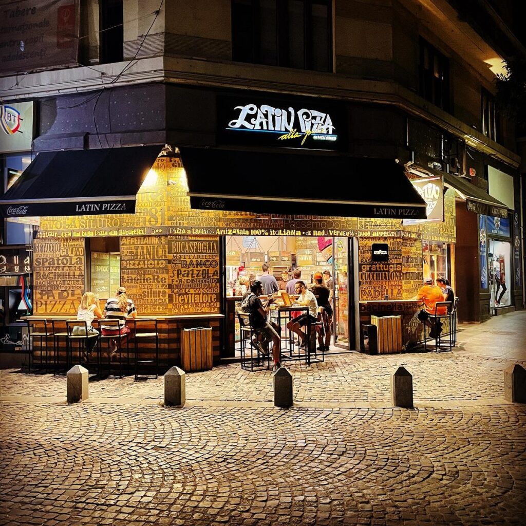 pizzeria de strada Latin Pizza din Bucuresti, fotografiata seara, cu oameni la masa pe strada