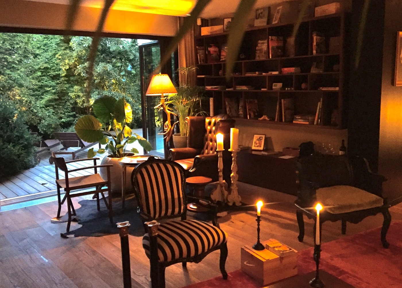living din Le Petit Chalet, cu lumanari aprinse, un scaun in stil clasic si o bliblioteca pe pereti si o veioză - una din destinații romantice din România