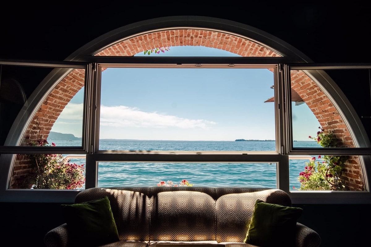 fereastra boltita prin care se vede lacul Garda, cu o canapea asezata n dreptul ei, la interioru restaurantului Lido 84 din Italia, unul cin cele mai bune restaurante din lume