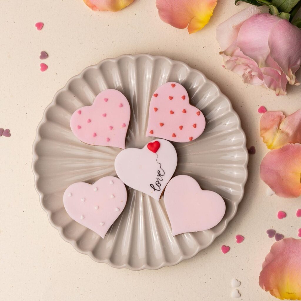 farfurie in care snt asezati 5 biscuiti in forma de inima, ornati cu roz, de la Mara Mura, de unde sa-i oferi ceva dulce de Ziua Îndrăgostiților