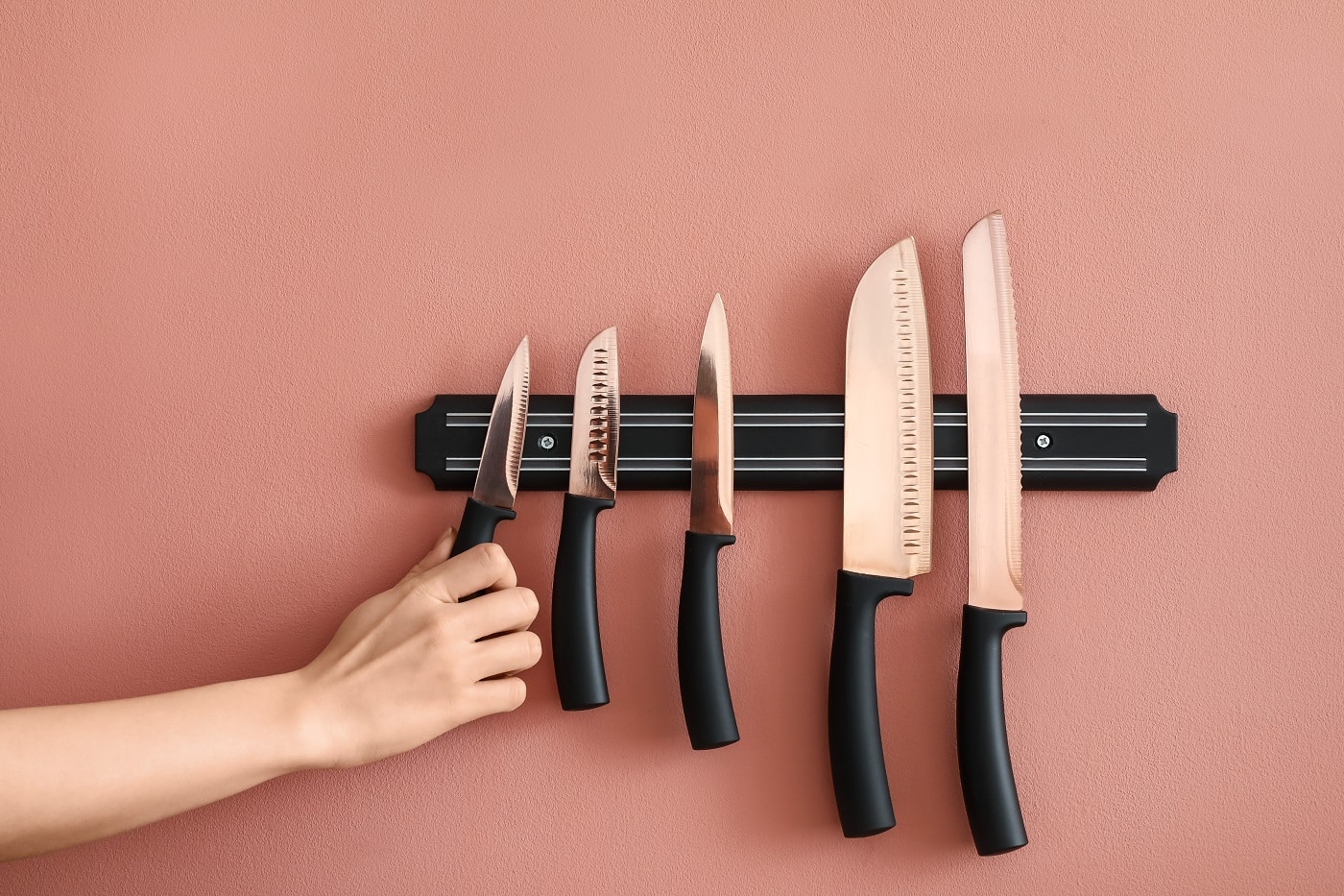 5 tipuri de cuțite diferite, prinse pe o banda magnetica, pe un perete roz